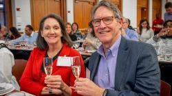 A man and woman holding glasses smiling.